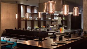 Un restaurant moderne doté d’un long comptoir, de plusieurs espaces de restauration et d’un éclairage de style industriel.