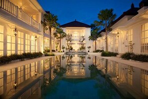 A luxurious hotel with a central reflecting pool, elegant architecture, and well-maintained gardens. - The Colony Hotel (Seminyak)