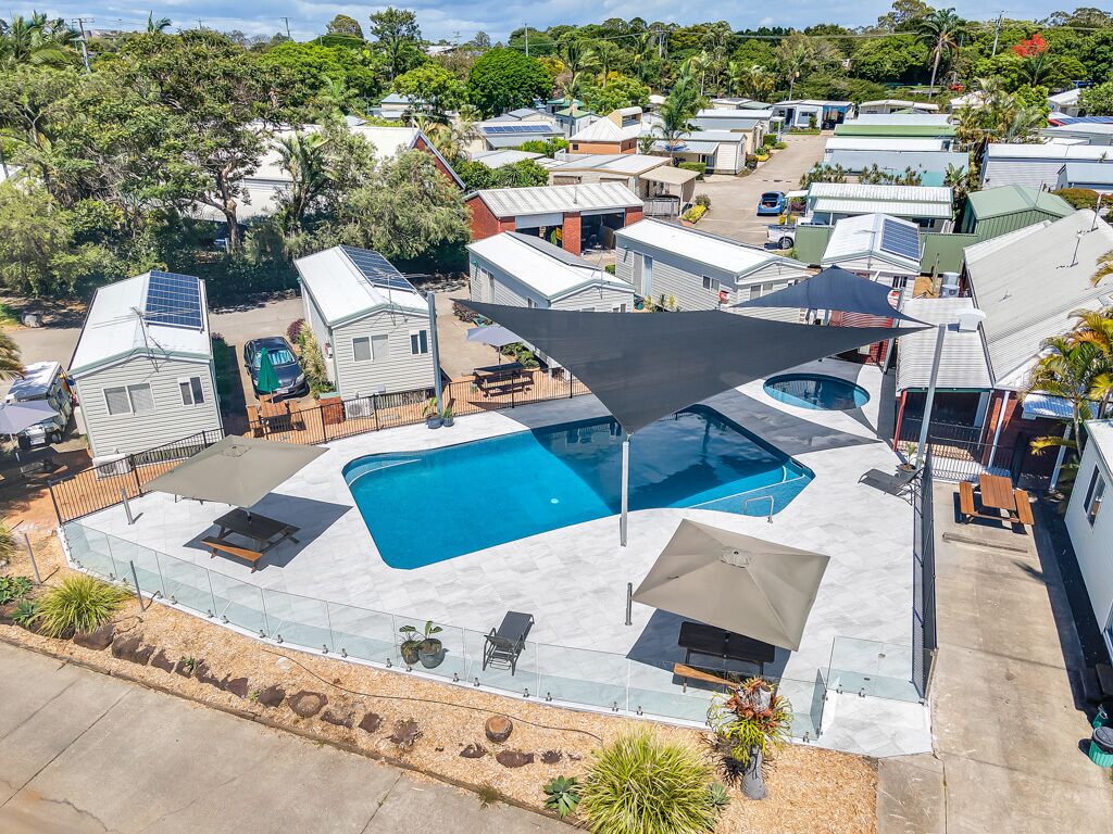 A residential area with multiple mobile homes, a swimming pool, and a patio area with outdoor furniture.