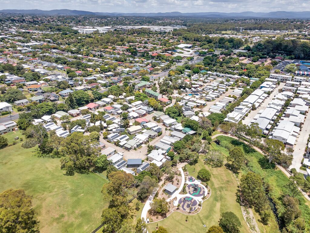 An aerial view of a residential area with houses, green spaces, and a playground.