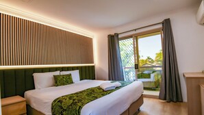 Une chambre d’hôtel avec un lit, une table de chevet, un bureau et une vue sur l’extérieur.
