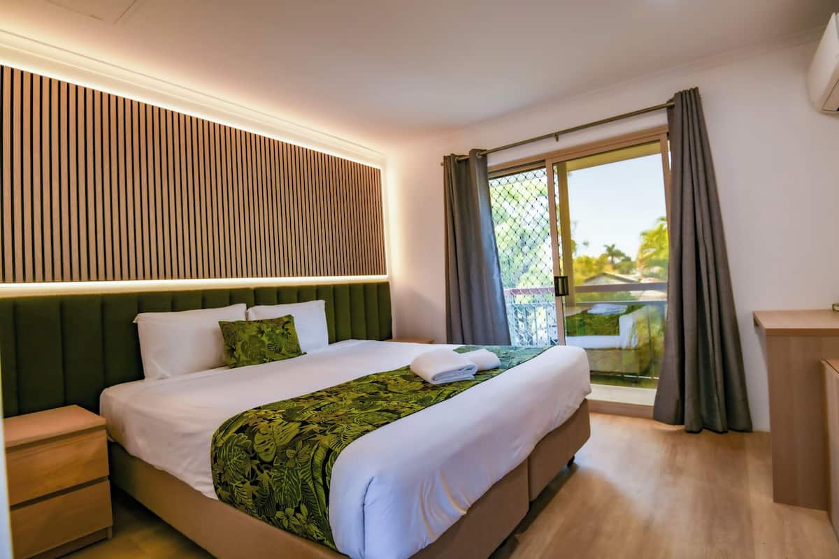 Une chambre d’hôtel avec un lit, une table de chevet, un bureau et une vue sur l’extérieur.