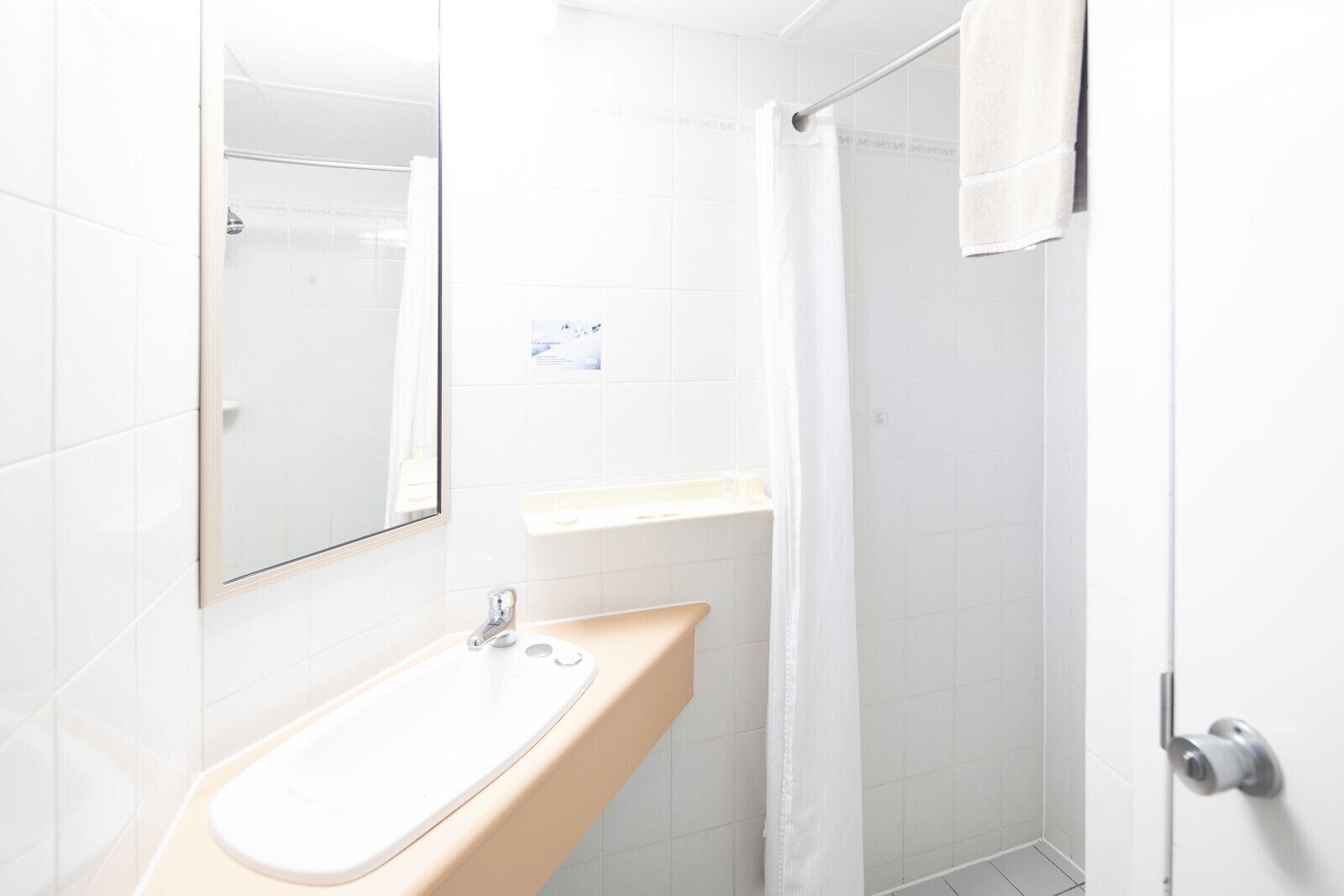 A bathroom with a sink, mirror, and shower.
