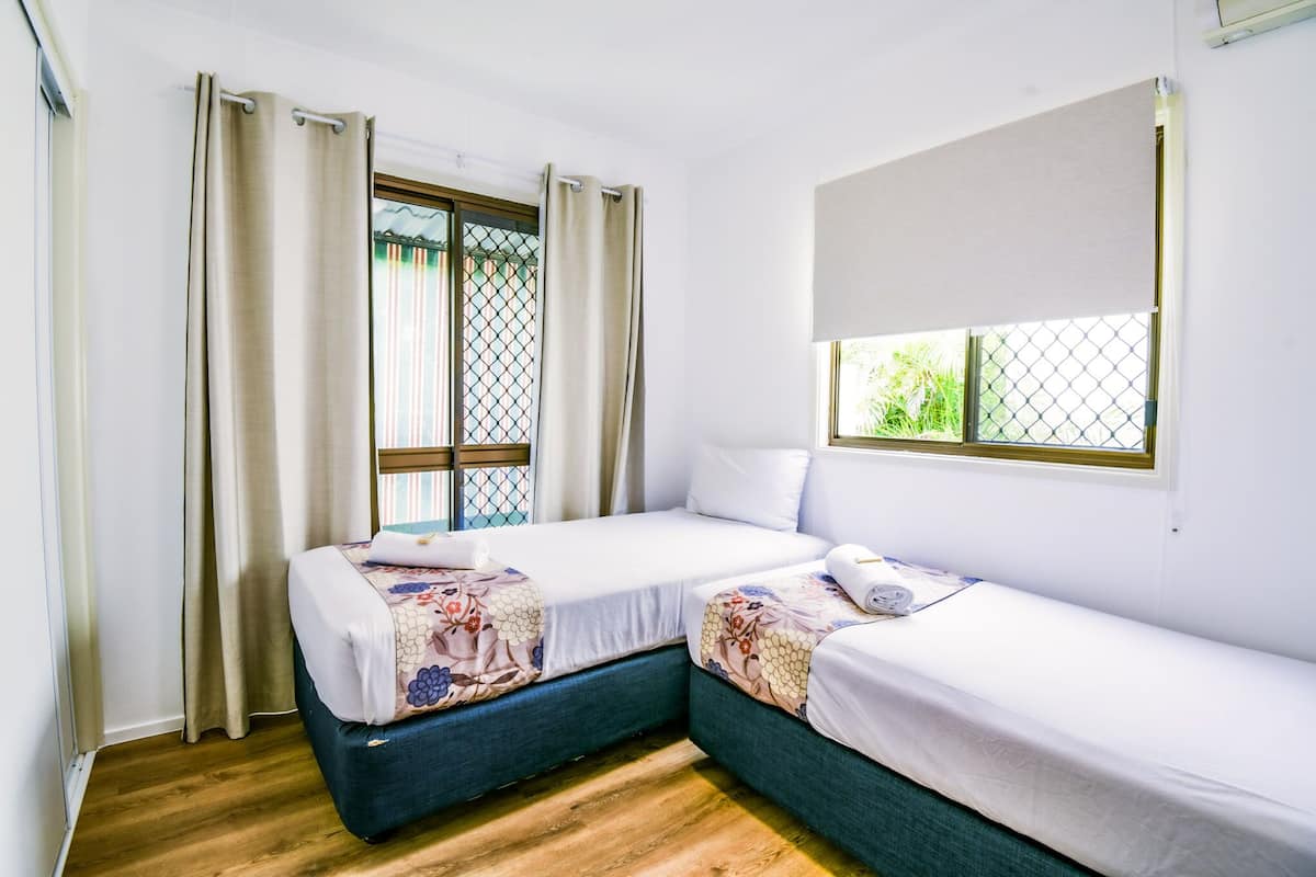 Une chambre avec deux lits, une fenêtre donnant sur un beau paysage et un rideau.