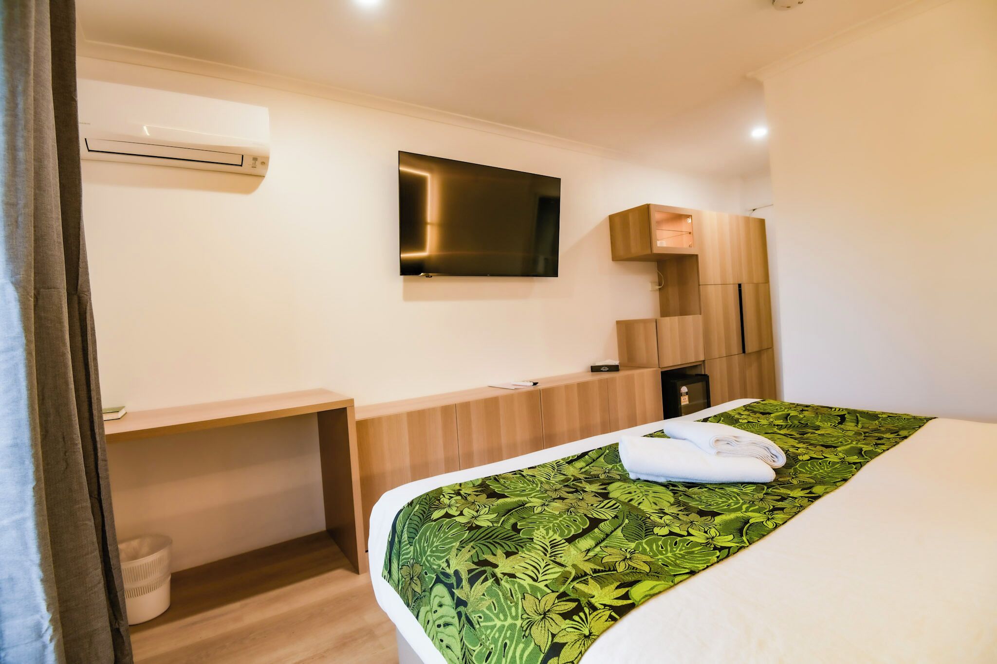 Una camera d'hotel con un letto, una scrivania, una TV a schermo piatto e un armadio a muro.