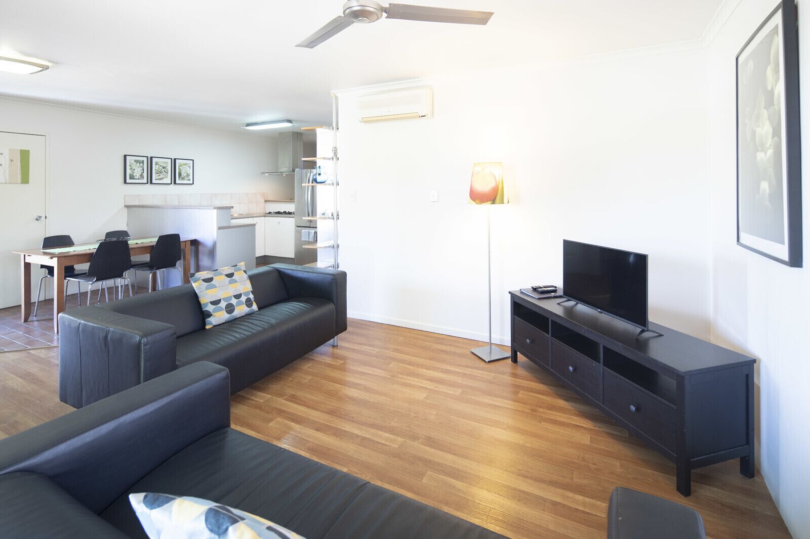 Ein modernes Wohnzimmer mit einer Couch, einem Fernseher und einem Essbereich mit Stühlen und einem Tisch.