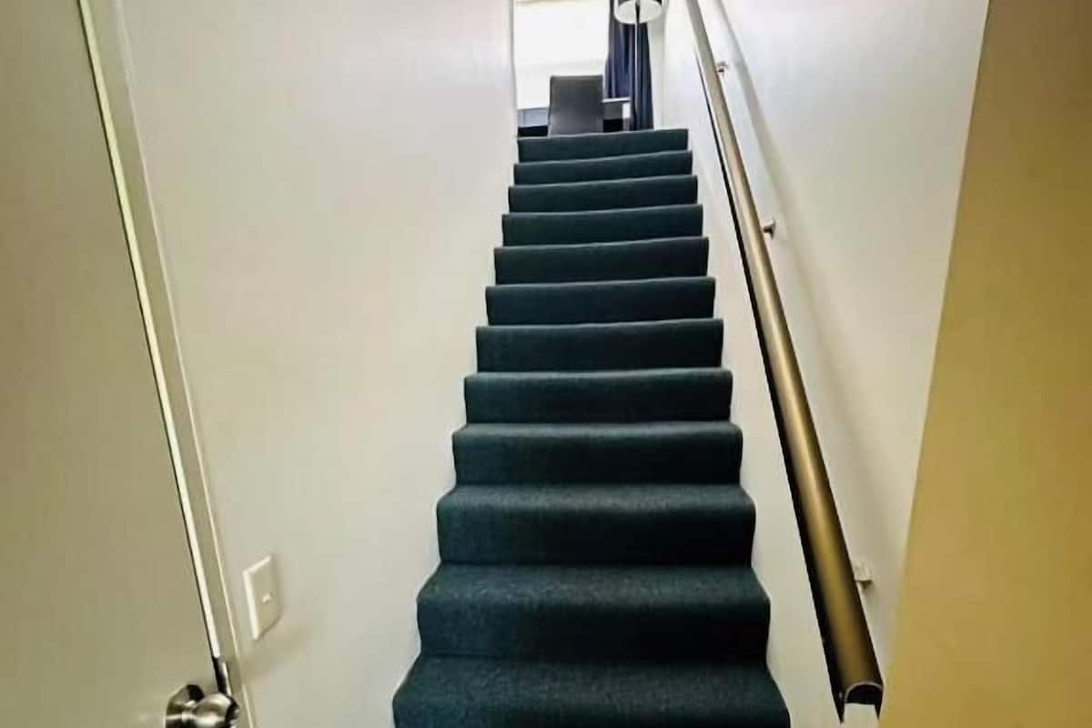 Una escalera con barandilla y una puerta al final.