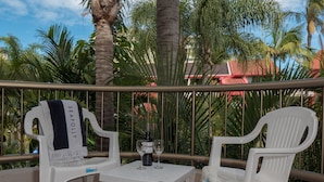 Een balkon met twee witte plastic stoelen, een tafeltje en een fles wijn.