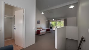 Een hotelkamer met twee bedden, een douche en een balkon met uitzicht op groen.
