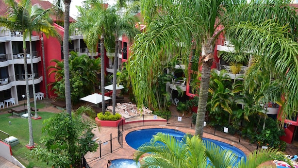 Een hotel met een zwembad, palmbomen en terrasjes.