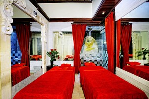 Camera d'albergo con due letti coperti di lenzuola rosse, un grande specchio e tende rosse.