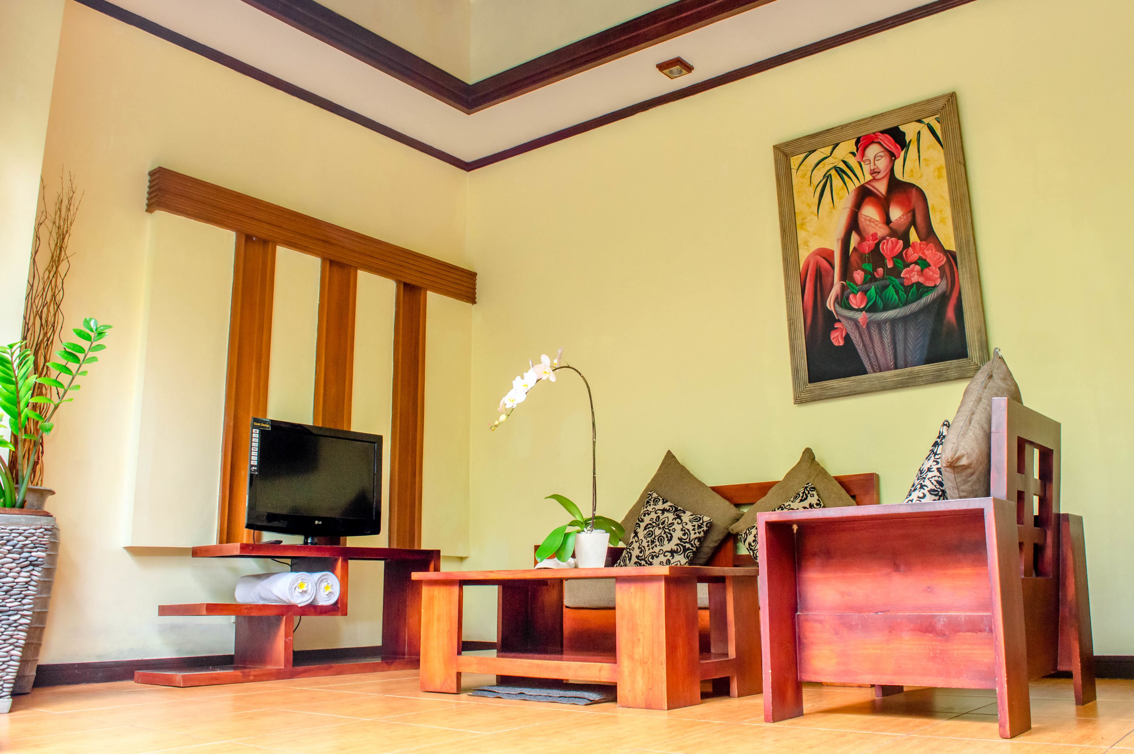 A living room with a television, a sofa, a coffee table, and a painting on the wall.