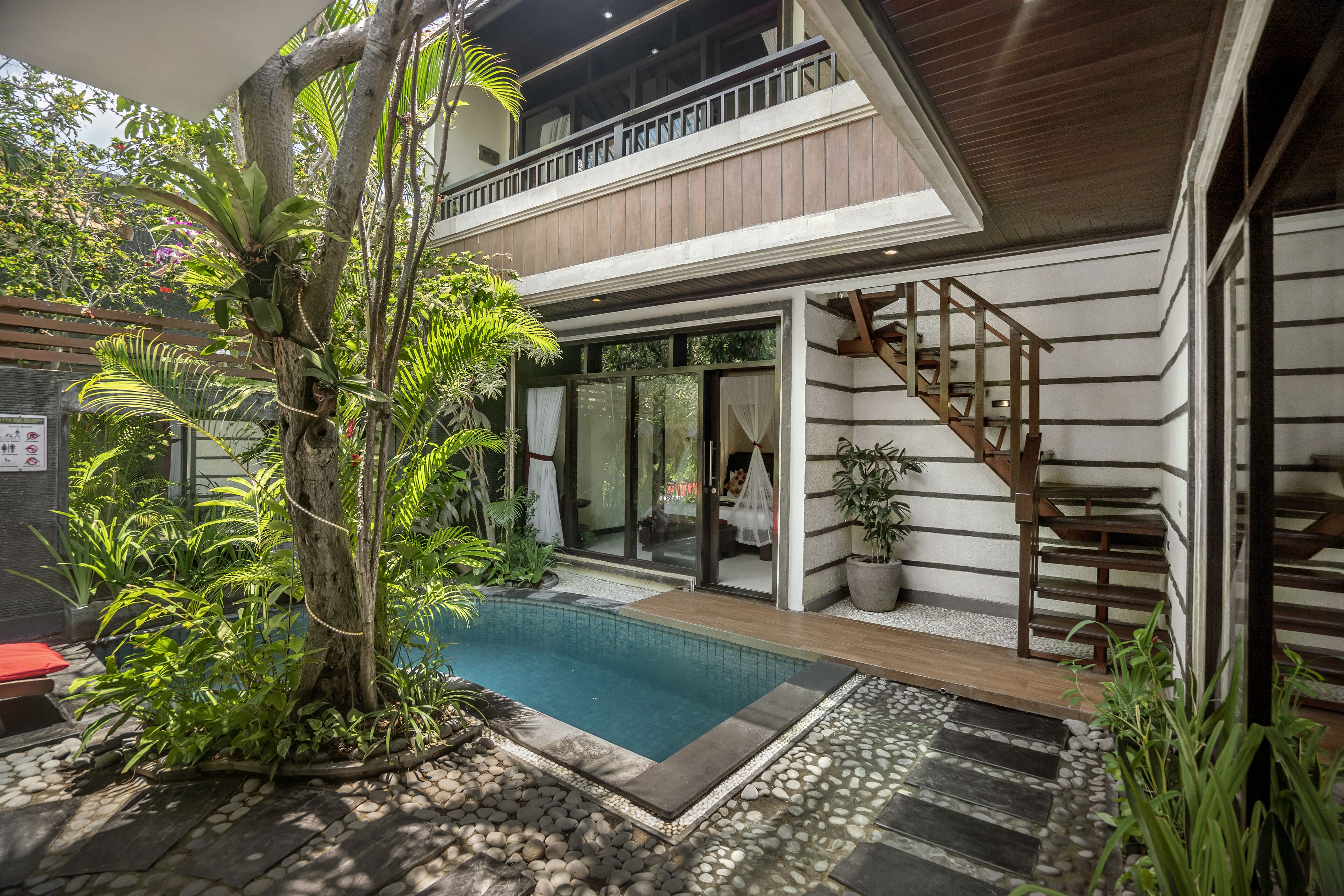 Et moderne hus med swimmingpool, trappe og frodigt grønt område.