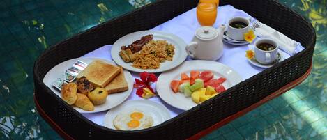 A breakfast tray with toast, eggs, bacon, and fruit by a pool.