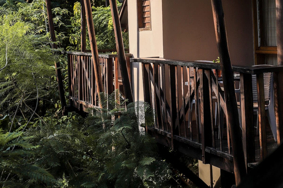 Una cabaña de madera con techo verde, un balcón y una ventana.