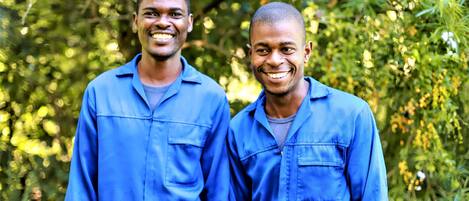 Two individuals in blue work uniforms standing outdoors.