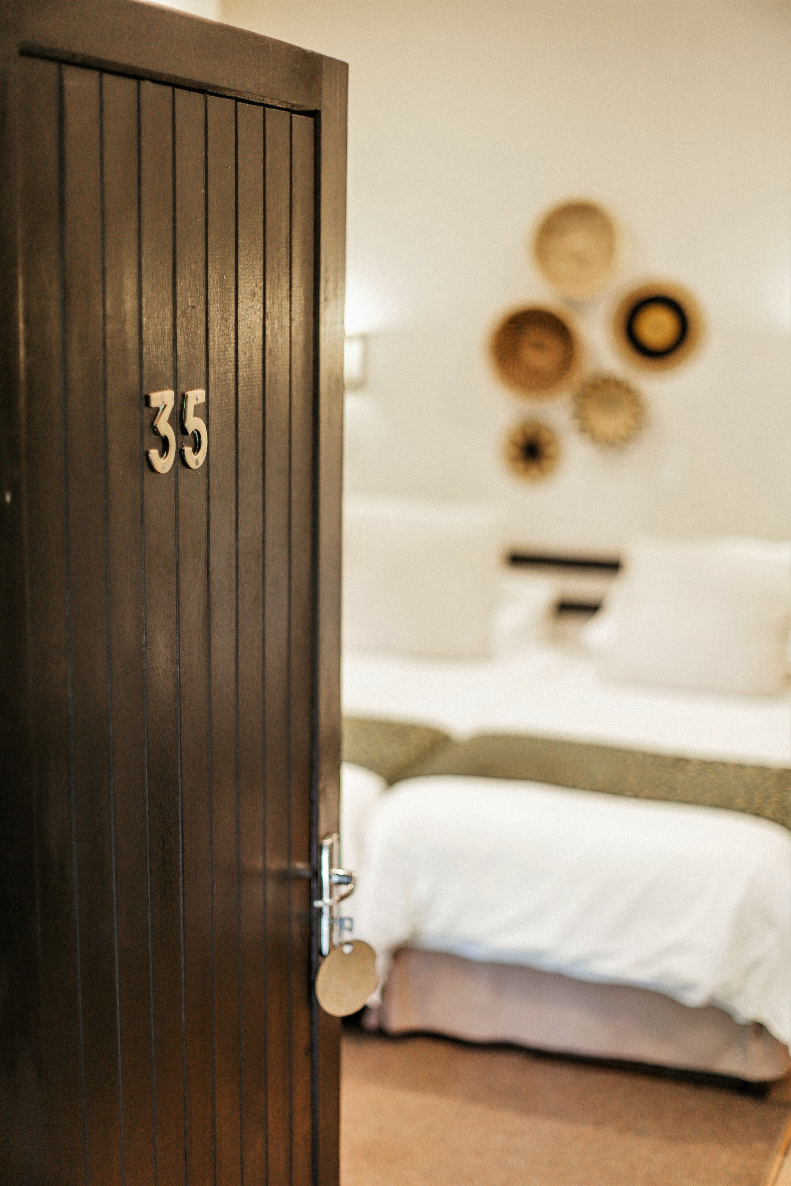 A wooden door with the number 35, leading to a room with a bed and a wall with circular decorations.