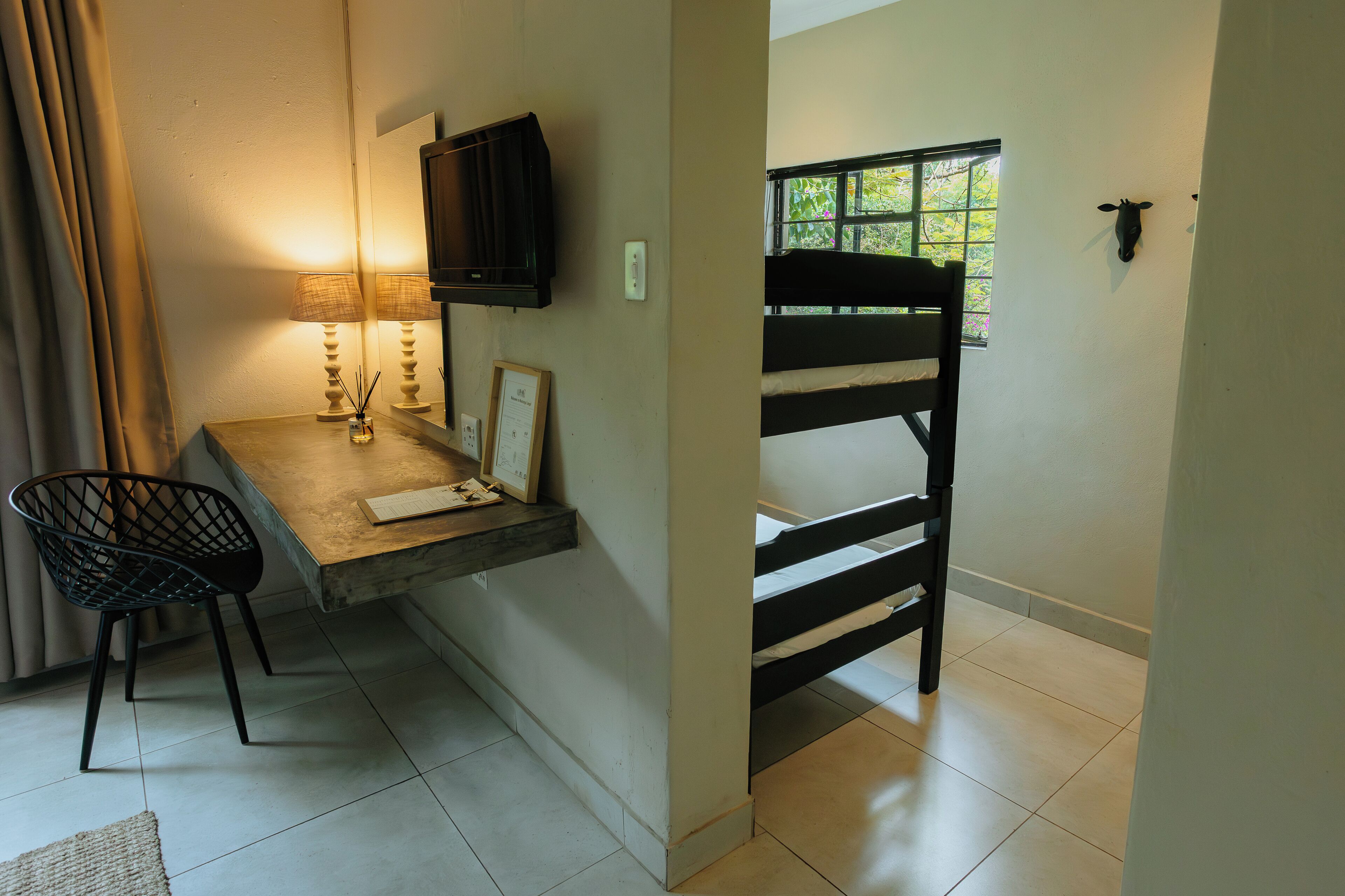 Una habitación pequeña con escritorio, silla, literas y un televisor montado en la pared.