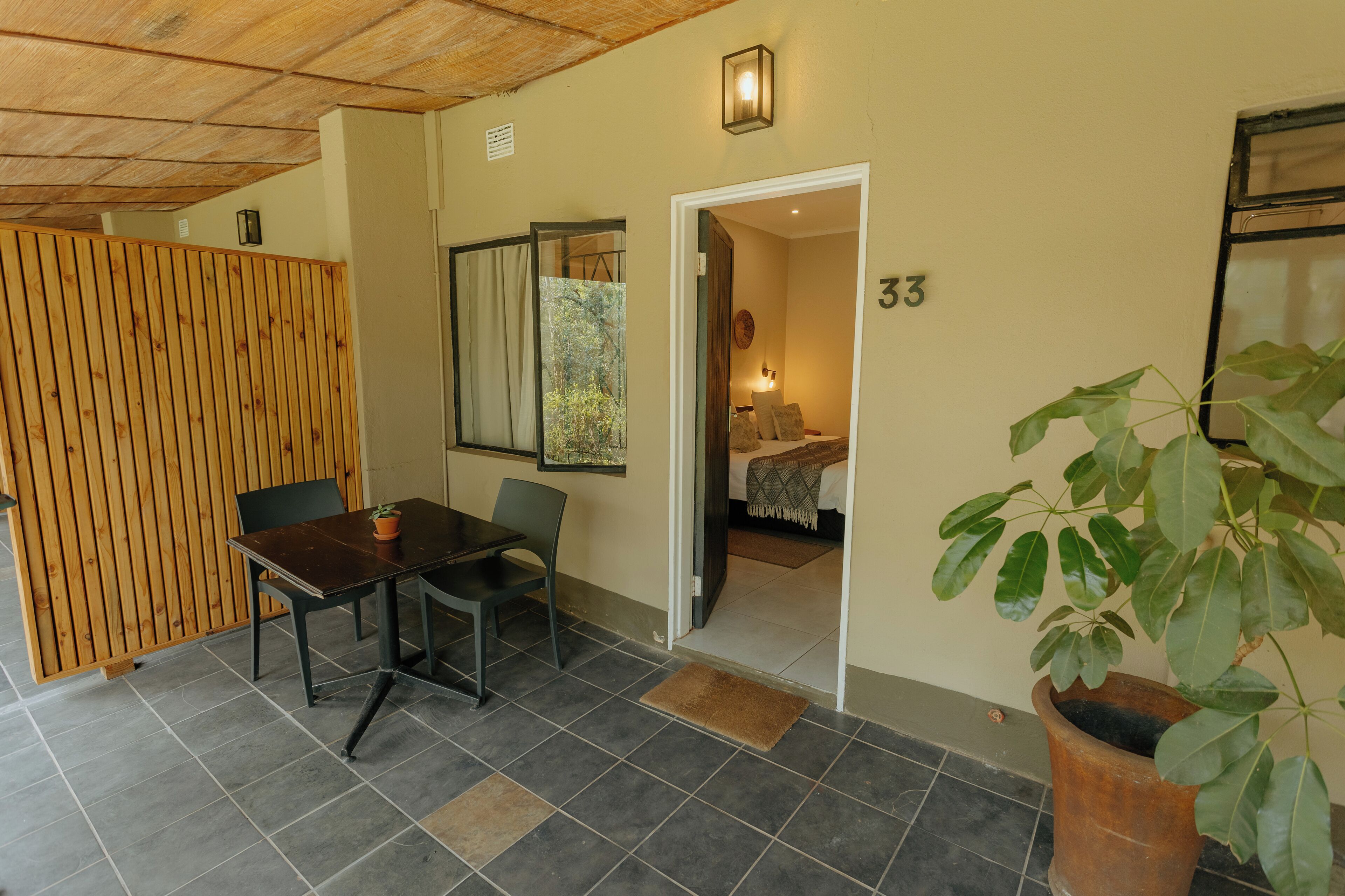 A room with a wooden partition, a table with chairs, a potted plant, and a door leading to another room.