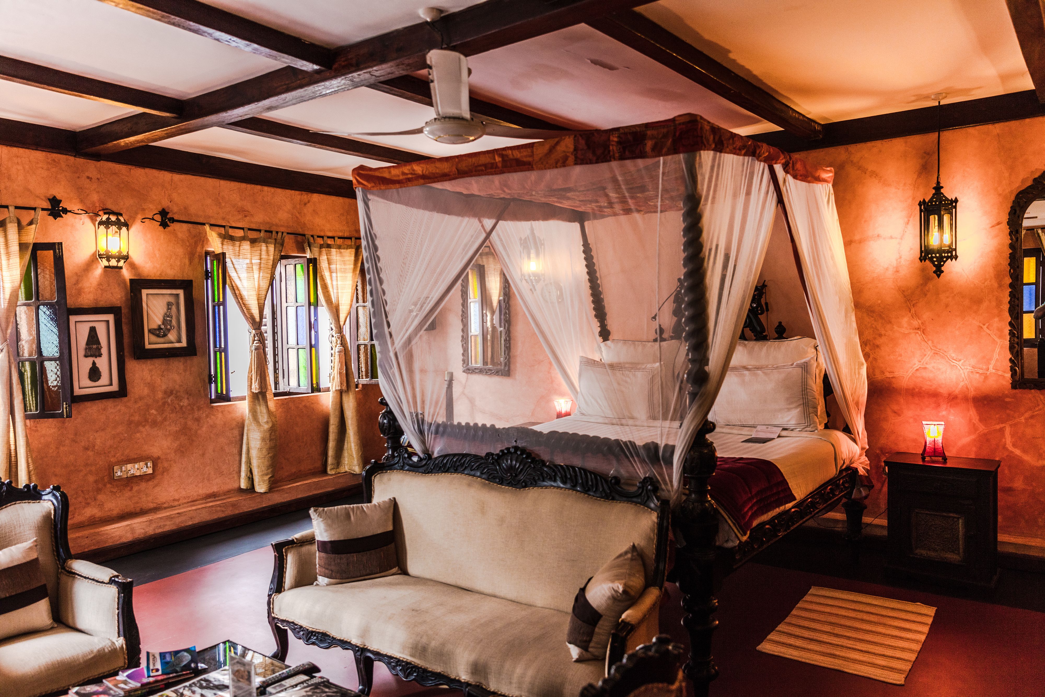 A room with a four-poster bed, a sofa, and a small table.