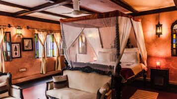 A room with a four-poster bed, a sofa, and a small table.