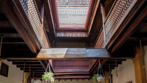A spacious interior with a high ceiling, wooden beams, and a central open area with a view to the upper level. - Jafferji House (Zanzibar Town)