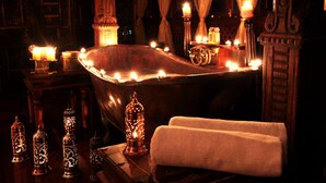 A dimly lit room with a bathtub, candles, and decorative lanterns. - Jafferji House (Zanzibar Town)