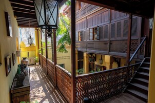 Un pasillo con barandillas de madera, una escalera y vista a un edificio de arquitectura tradicional.