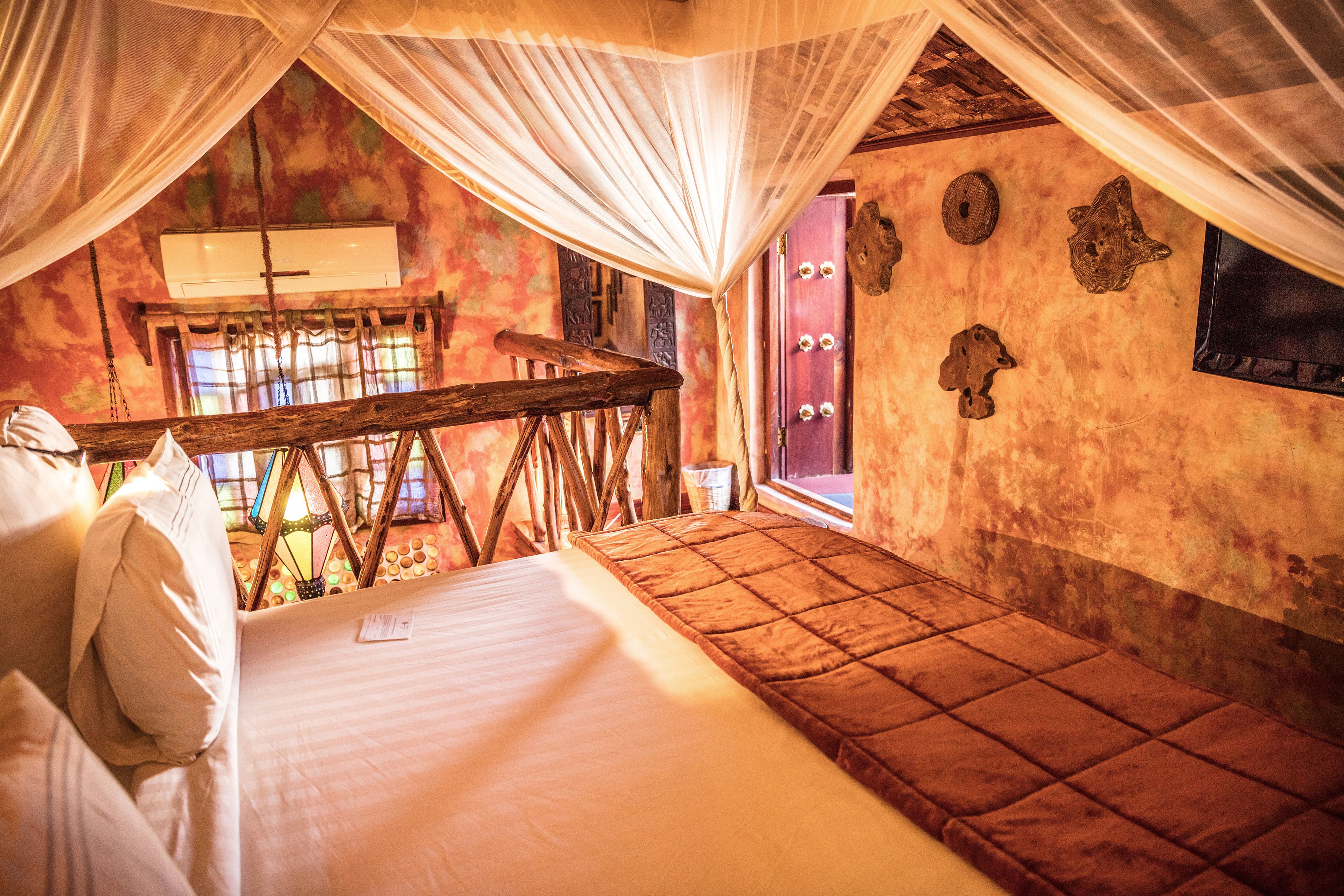 A room with a bed, a wooden bench, and a window with curtains.