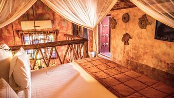 A room with a bed, a wooden bench, and a window with curtains.