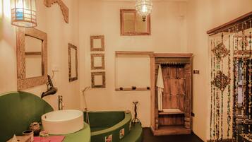 Un baño con una bañera verde, un lavabo blanco y una puerta de madera con cuentas decorativas.