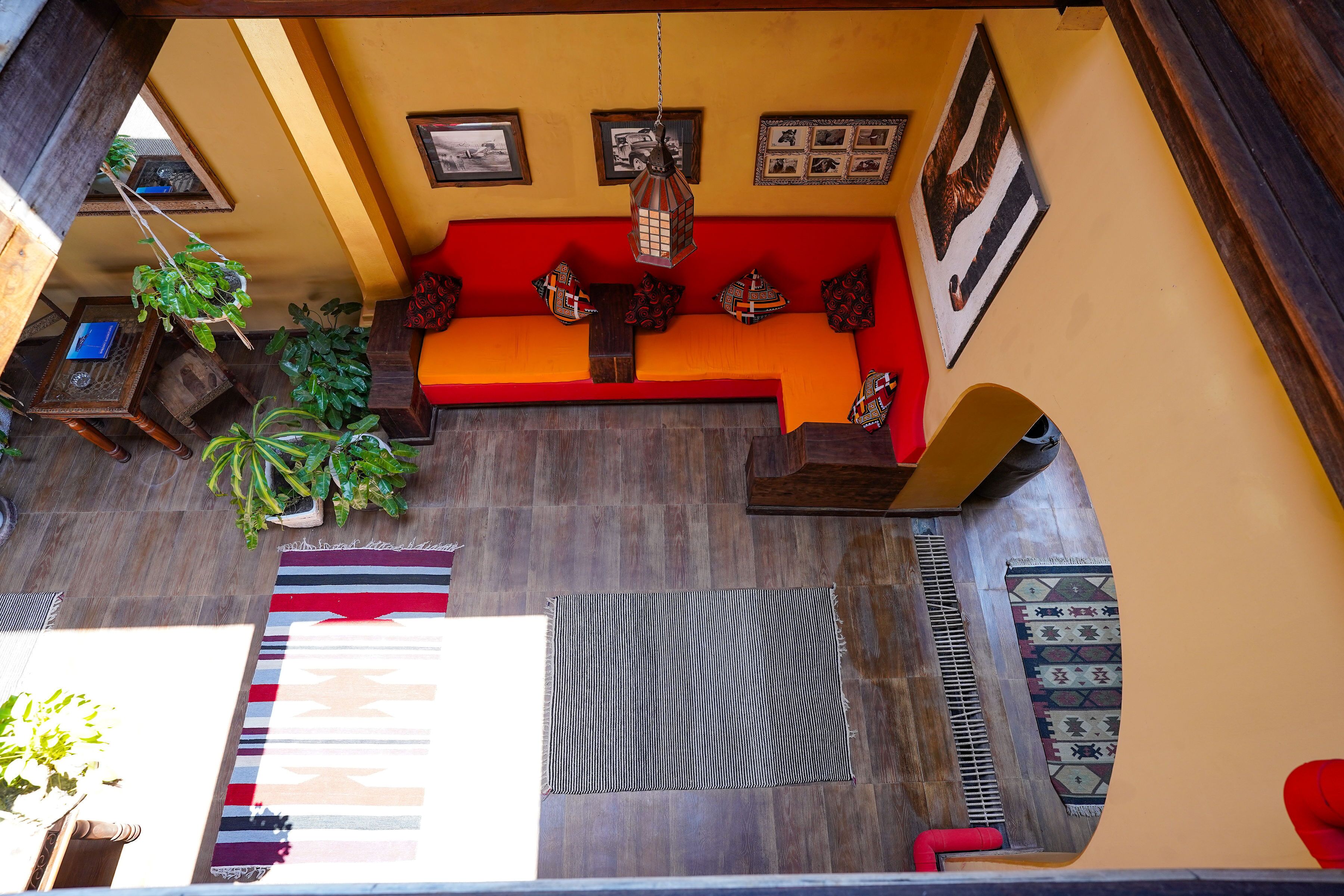 A room with a wooden floor, a red sofa, and various rugs.