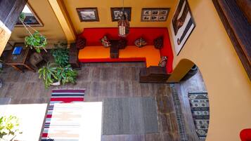A room with a wooden floor, a red sofa, and various rugs.