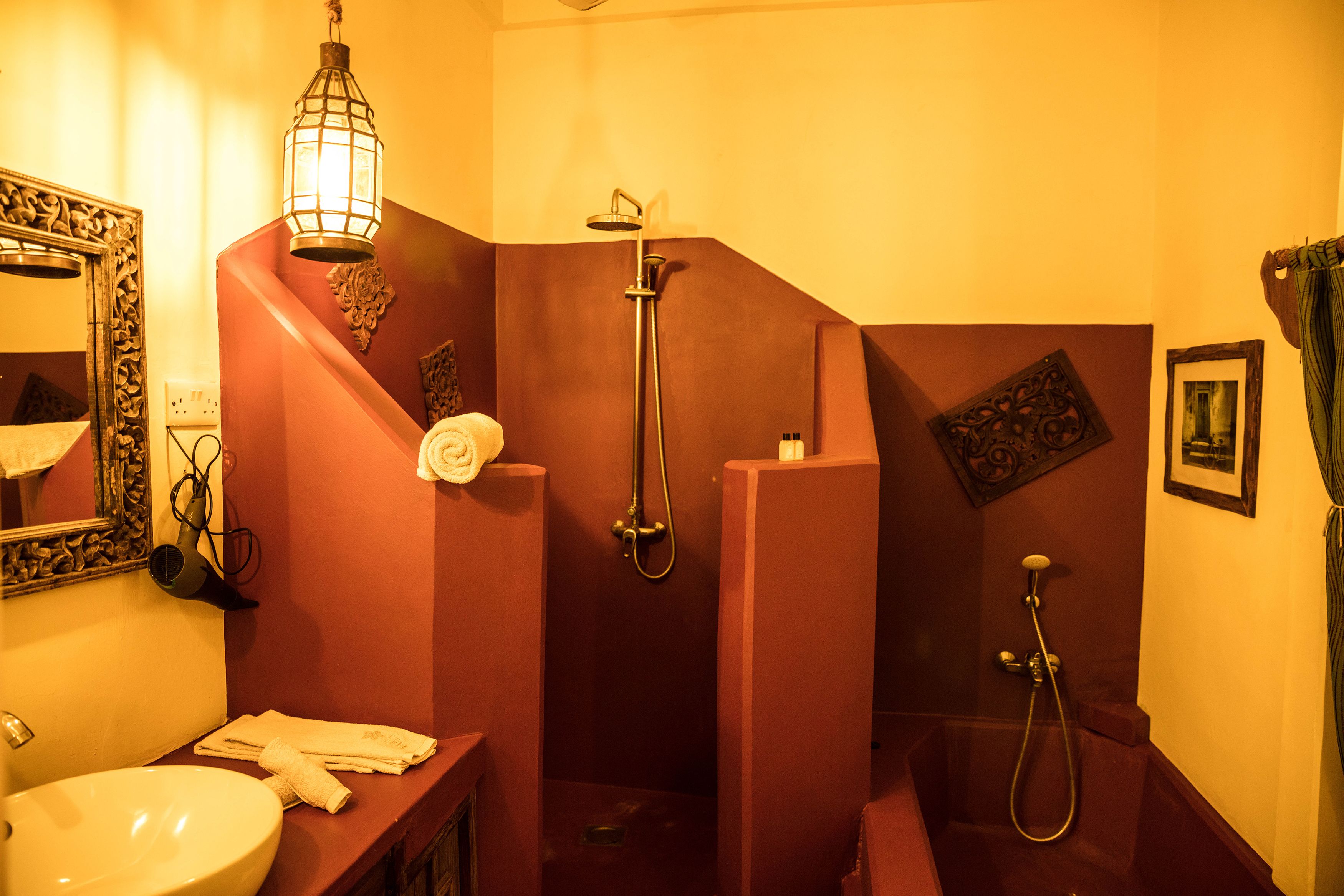 A bathroom with a sink, mirror, towel rack, and two showers.