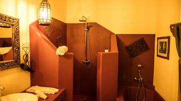 A bathroom with a sink, mirror, towel rack, and two showers.