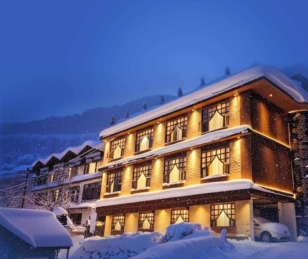 A multi-story hotel with a traditional architectural style, featuring a snow-covered exterior and warm lighting.