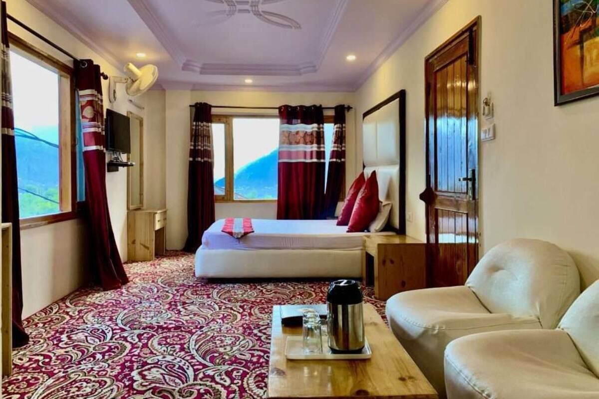 A hotel room with a bed, a sofa, a coffee table, and a large window with curtains.