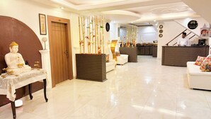 Un hall de hotel con mostrador de recepción, zona de estar y una estatua.
