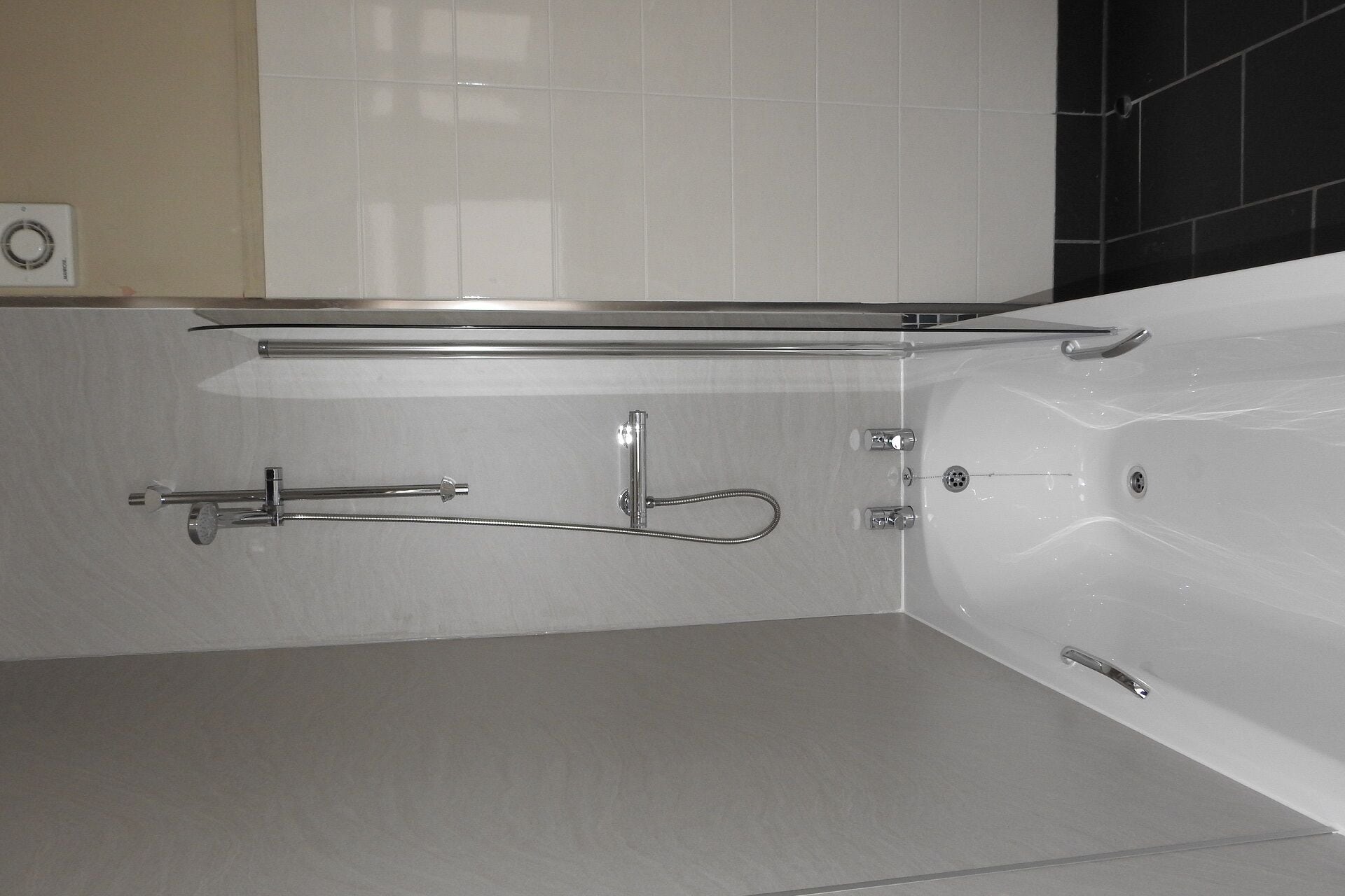 Un bagno moderno con una vasca, un soffione a mano e un porta asciugamani.