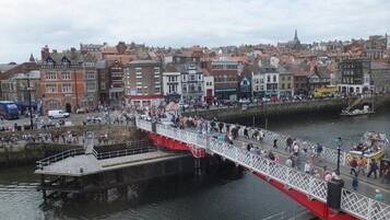 A pedestrian bridge over a body of water with buildings in the background.
