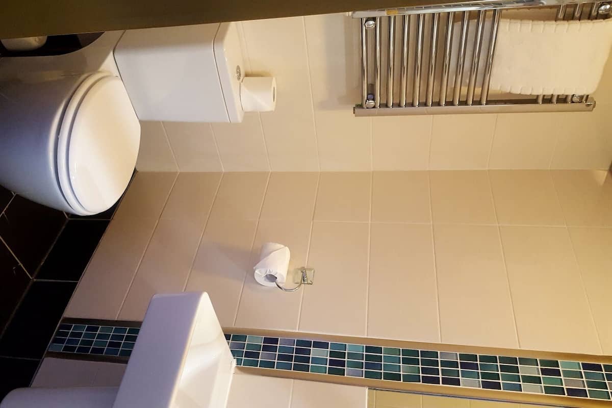 A bathroom with a toilet, a towel rack, and a toilet paper holder.