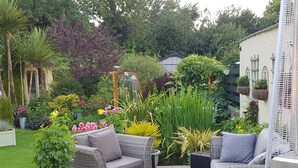 Un patio con muebles de mimbre y diversas plantas.