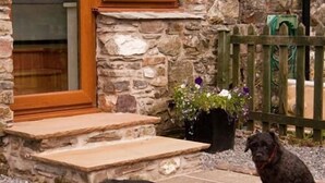 A stone building with a wooden door and steps leading to a porch. - Ghyll Farm Bed & Breakfast (Frizington)