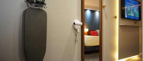 Una habitación de hotel con una plancha grande, un secador de pelo y un televisor en la pared.