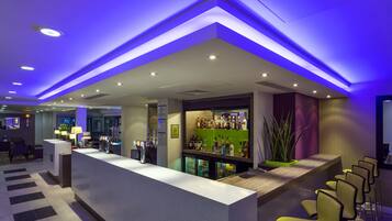 Un área de bar moderna con mostrador, asientos y una variedad de botellas.