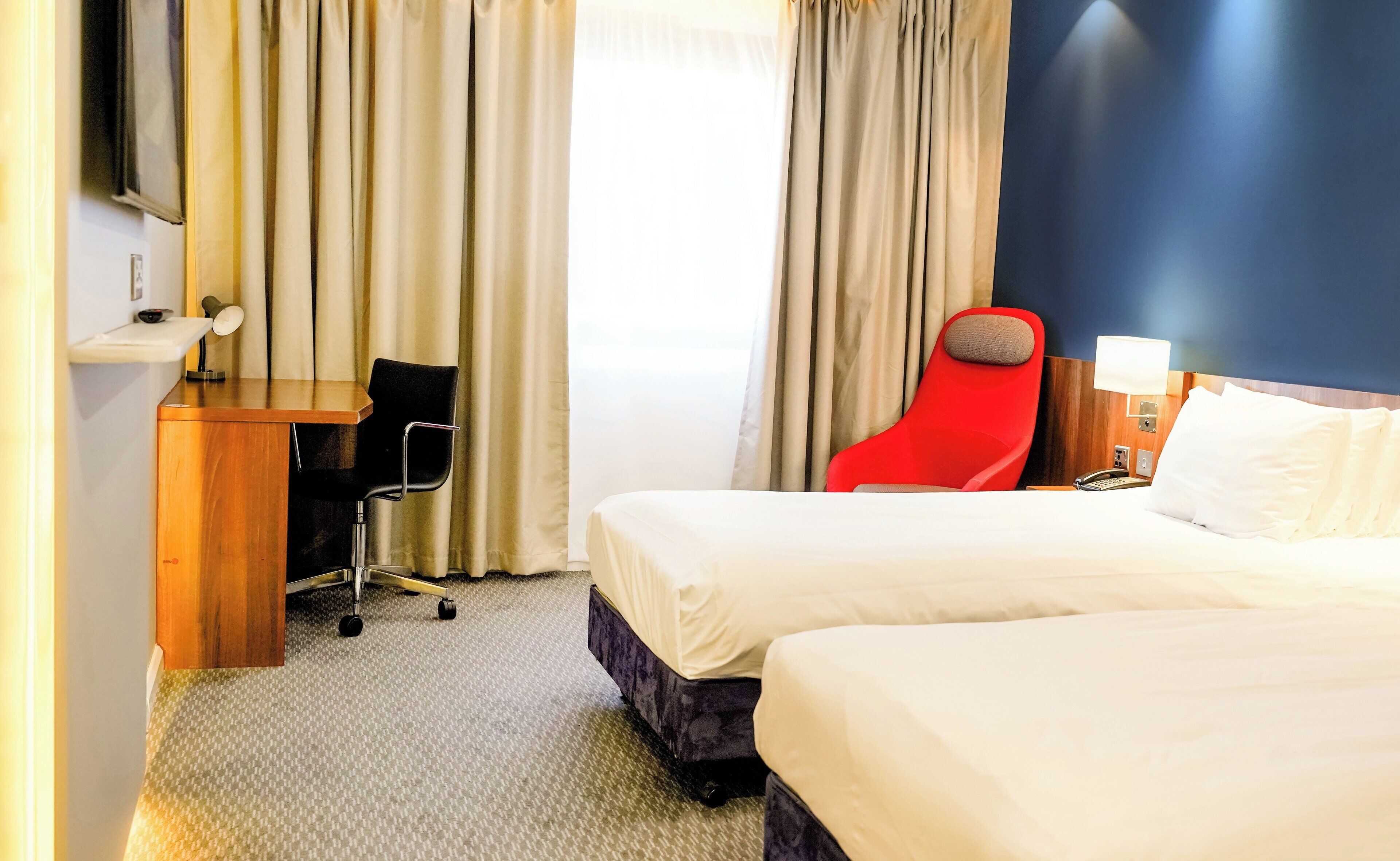 Una habitación de hotel con una cama, un escritorio, una silla y un teléfono.