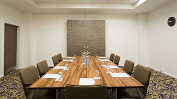A conference room with a long table, chairs, water bottles, and papers.