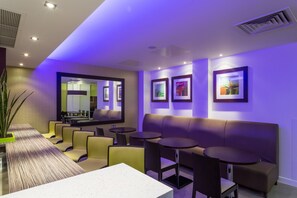 A modern lounge area with seating, tables, and artwork on the walls. - Holiday Inn Express Harlow by IHG (Harlow)