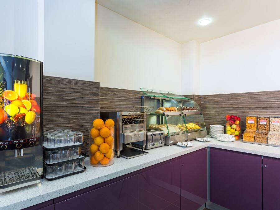 A buffet setup with a fruit display, a beverage dispenser, and various food items.