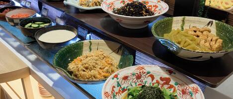 Buffet variado com diversos pratos, incluindo legumes, macarrão e frutos do mar.